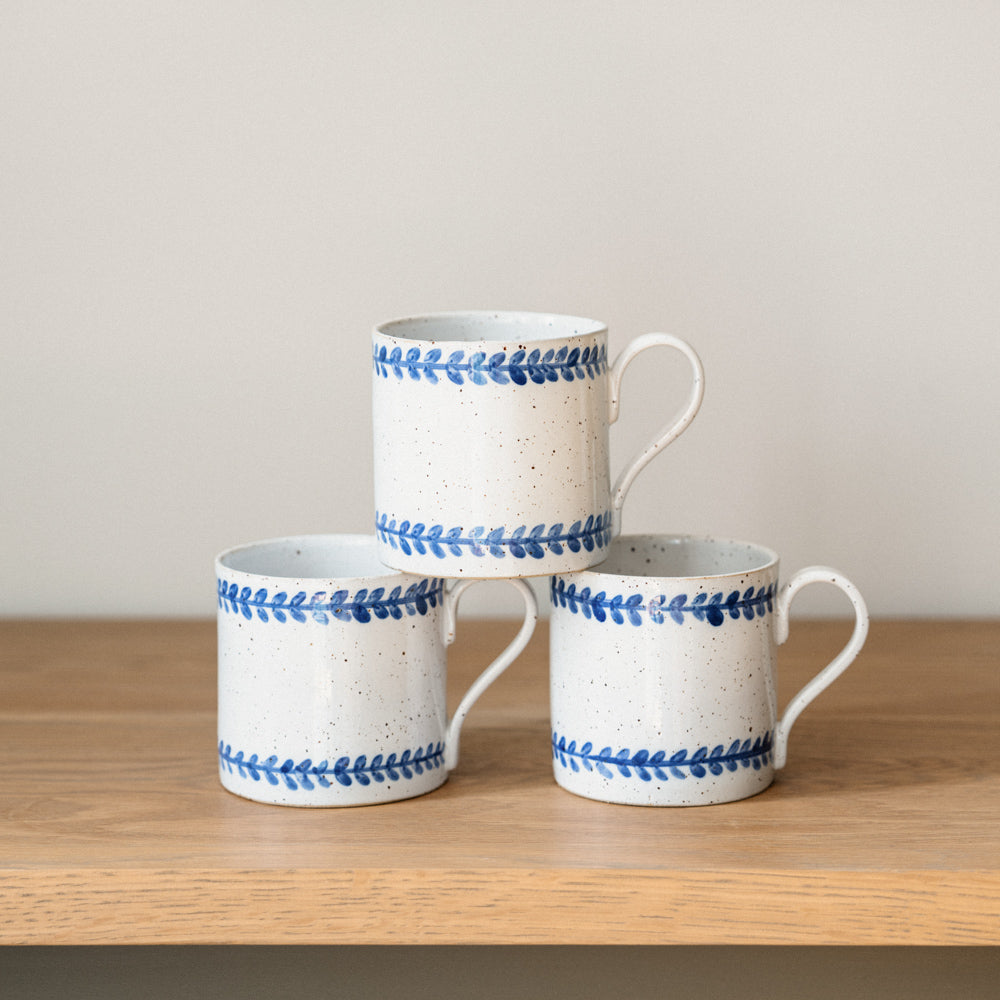 Handmade stoneware mug with hand-painted cobalt blue leaf border on a white glaze.