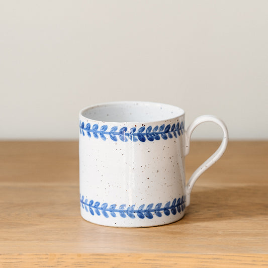 Handmade stoneware mug with hand-painted cobalt blue leaf border on a white glaze.