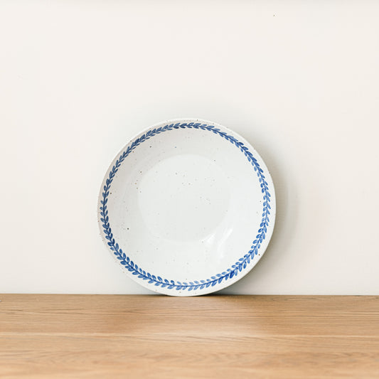 Handmade stoneware breakfast bowl with a hand-painted cobalt blue leaf border and glossy white glaze.