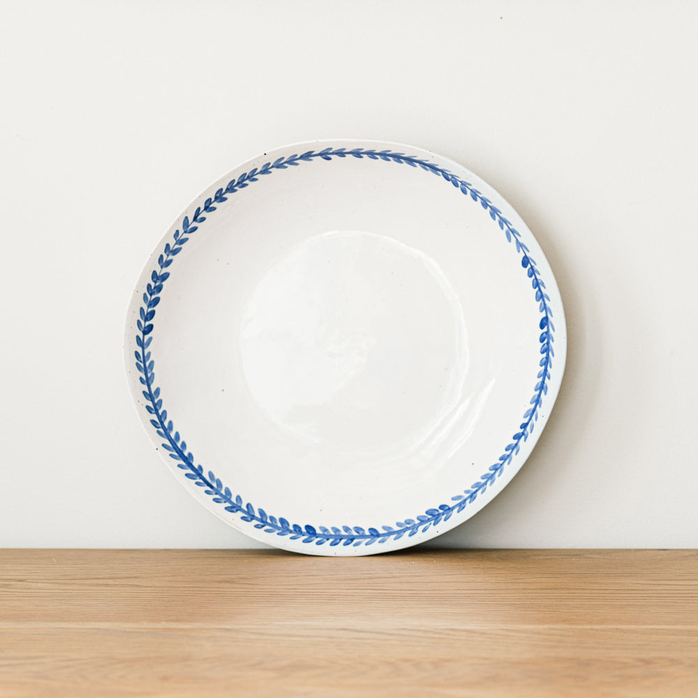 Handmade stoneware pasta bowl with a hand-painted cobalt blue leaf border and glossy white glaze.