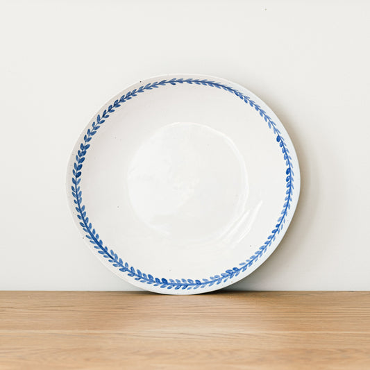 Handmade stoneware pasta bowl with a hand-painted cobalt blue leaf border and glossy white glaze.