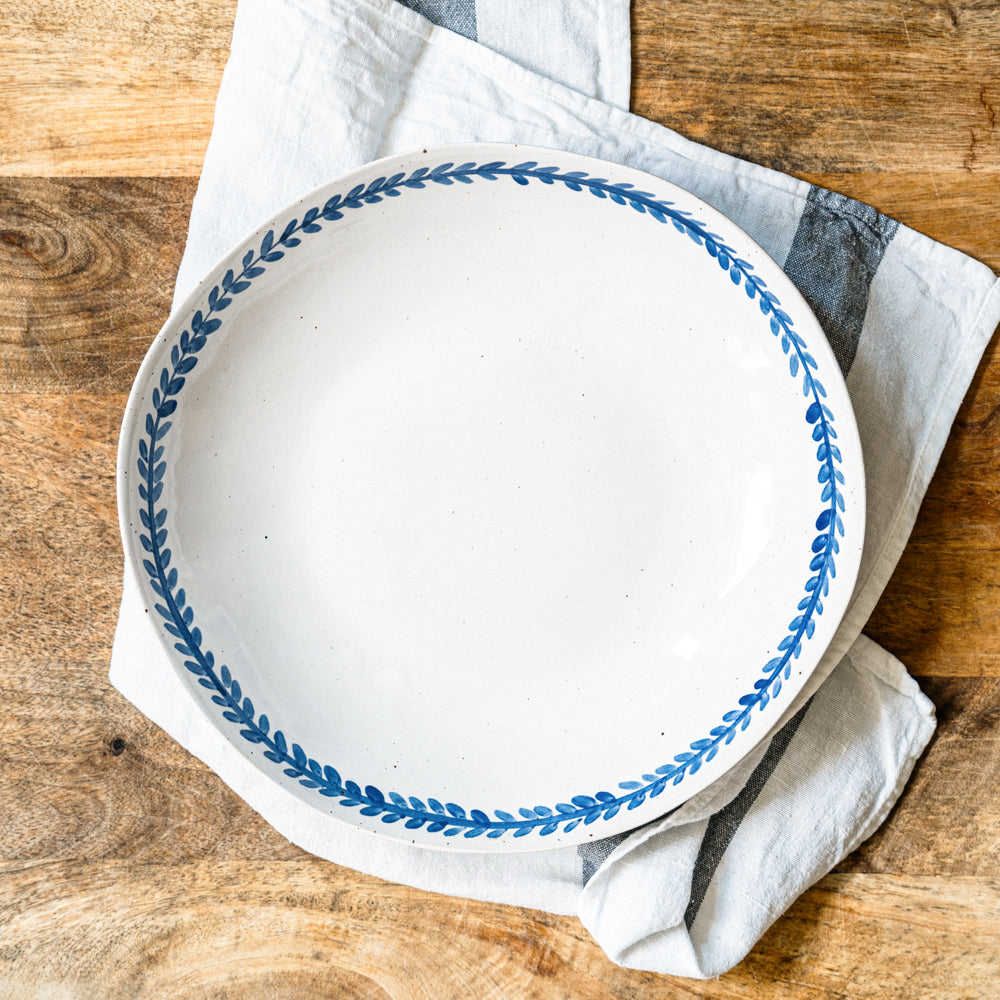 Overhead view of a handmade stoneware pasta bowl with cobalt blue decoration and a glossy white glaze.